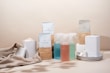 A minimalist arrangement of eco-friendly cleaning products including various bottles, containers, and packaging. The items are neatly placed on a soft beige fabric backdrop, emphasizing a sustainable and natural aesthetic.