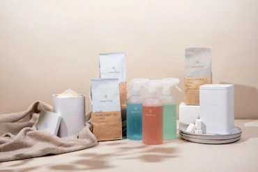 A friendly cleaning expert using green-certified products in a bright, modern living room.