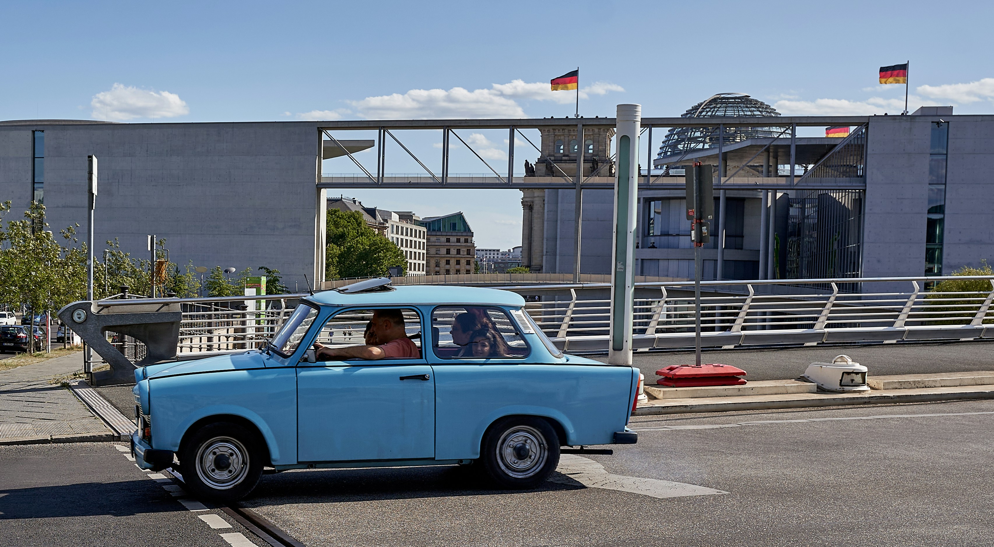a small blue car driving down a street