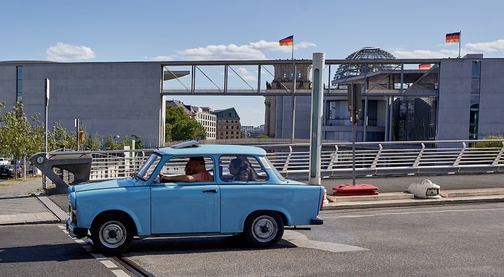 a small blue car driving down a street