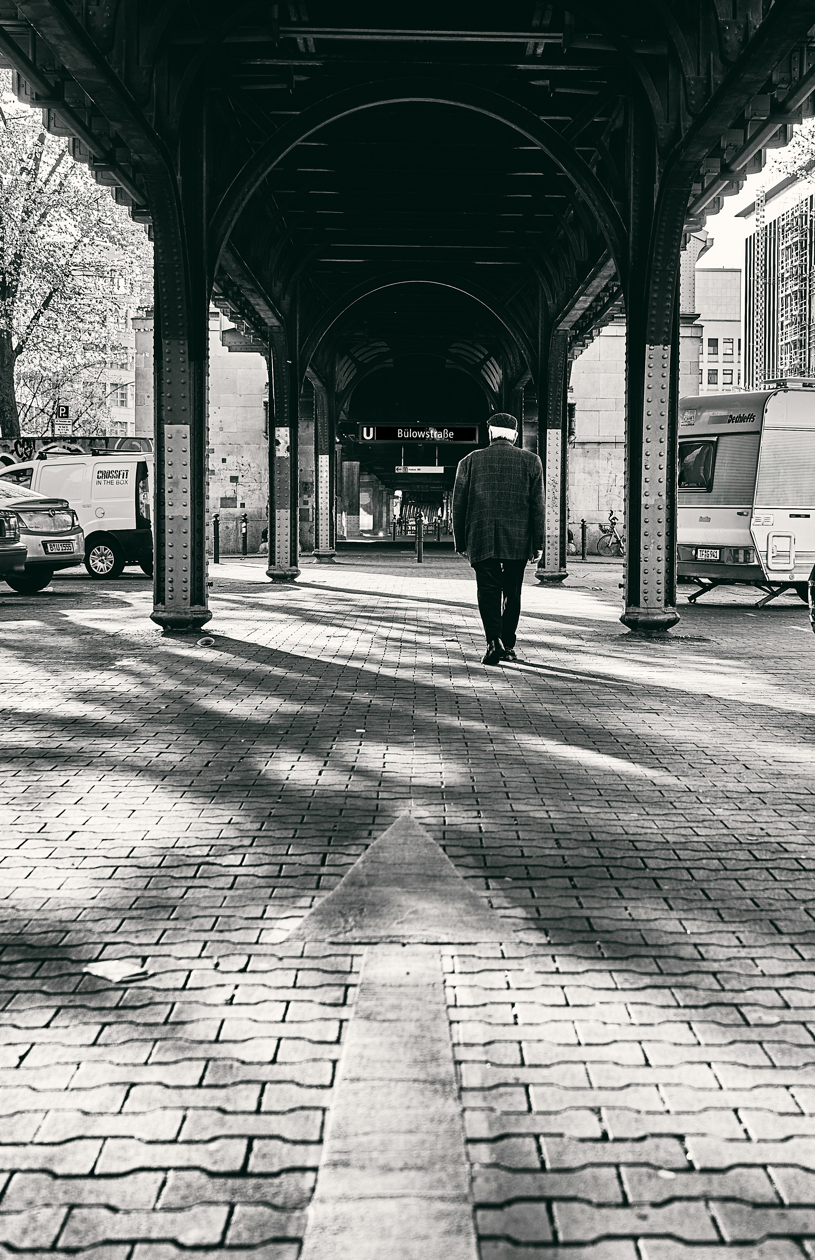 a man walking down a sidewalk under a covered walkway