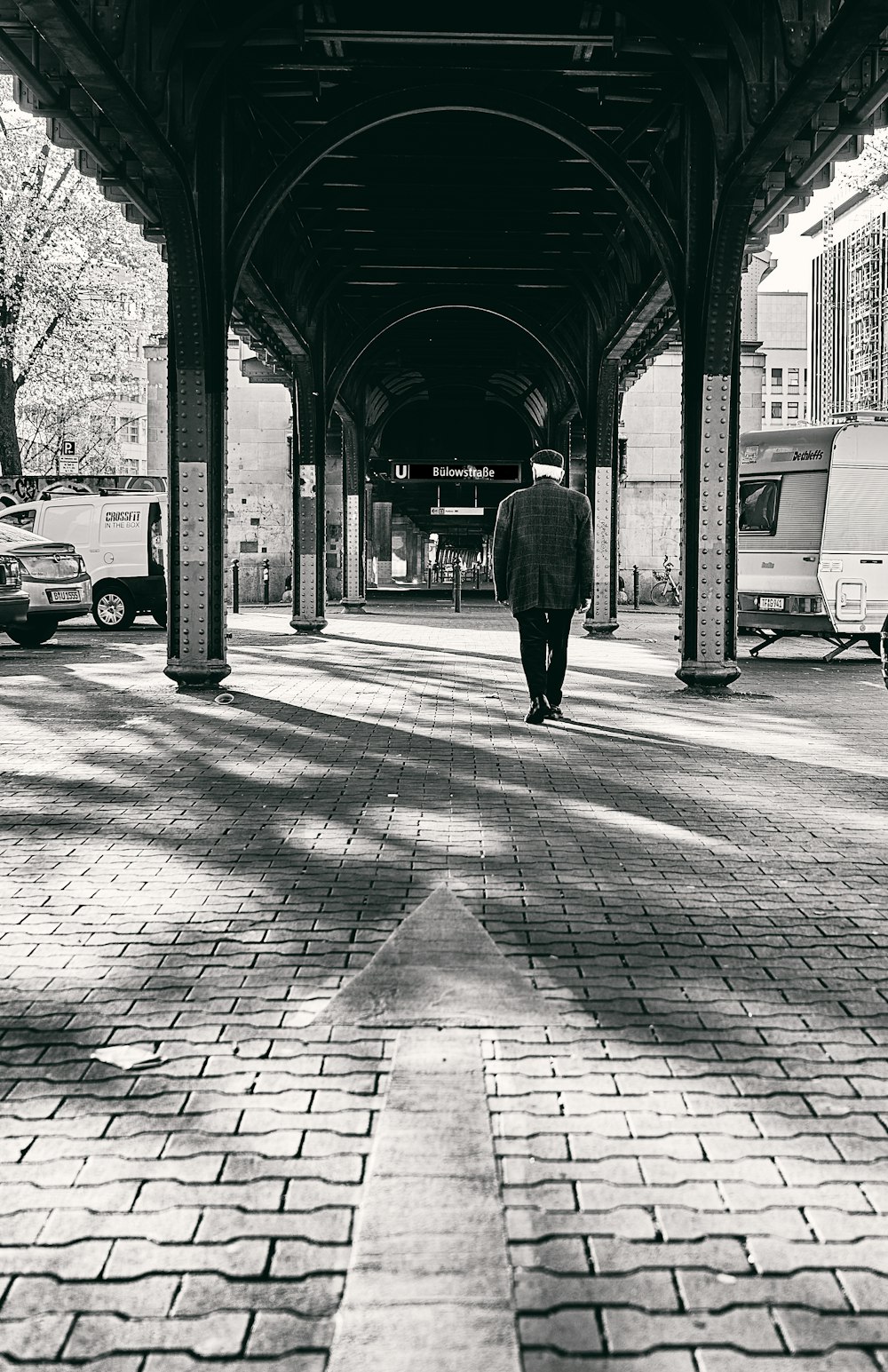 a man walking down a sidewalk under a covered walkway