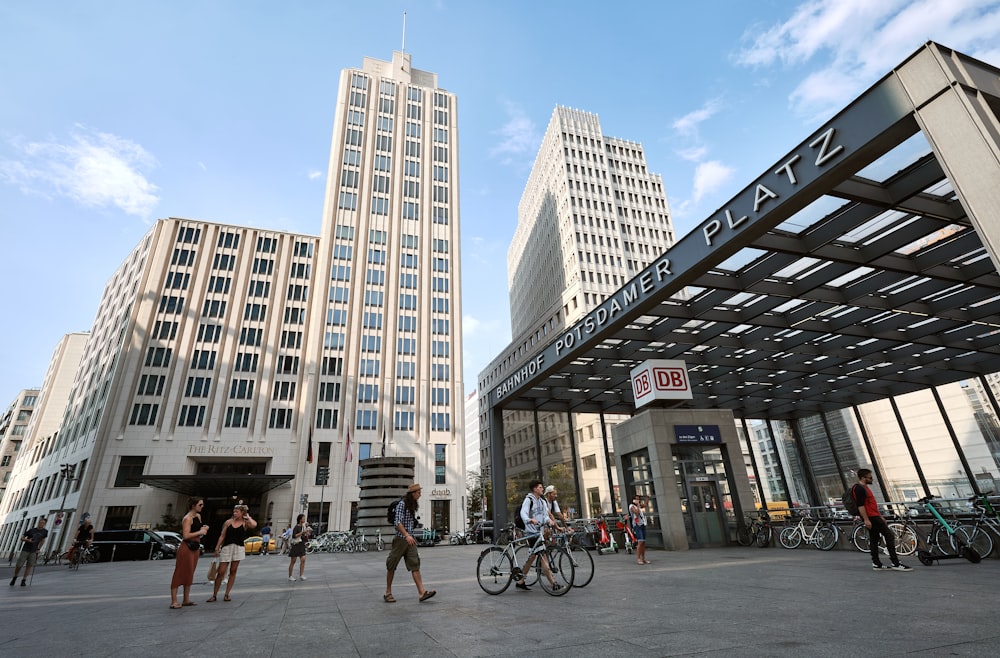 a group of people walking and riding bikes in front of tall buildings