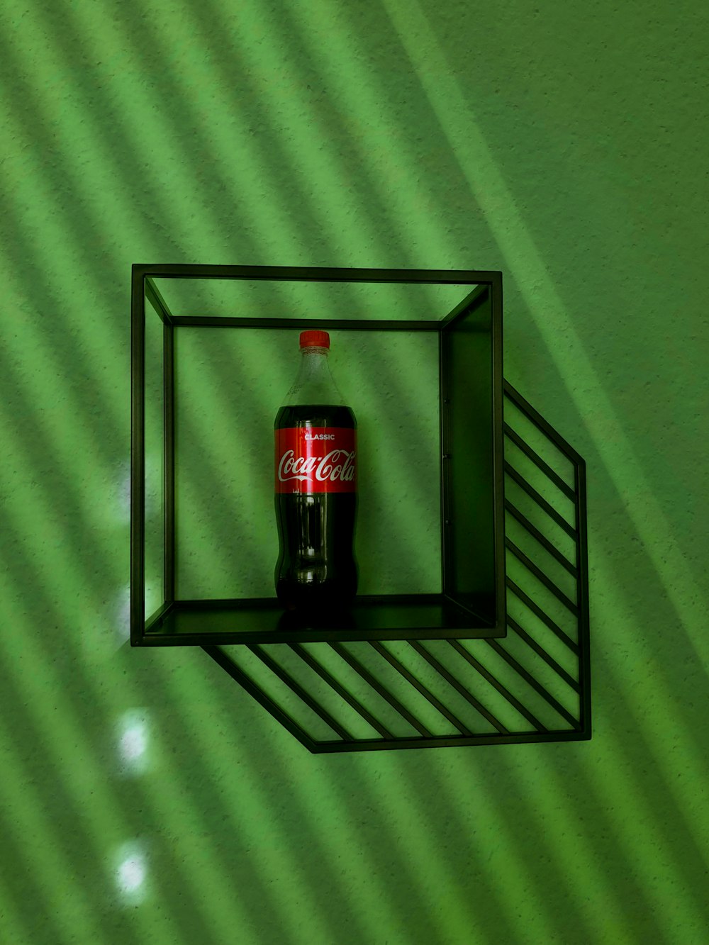 a coca - cola bottle in a shadow box on a green wall