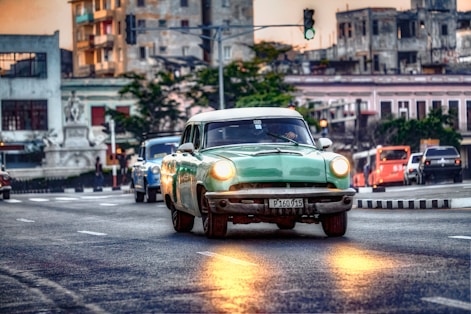 a green car driving down a street next to a traffic light