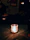 A softly lit room with a rustic candle burning on a wooden table surrounded by natural decor.