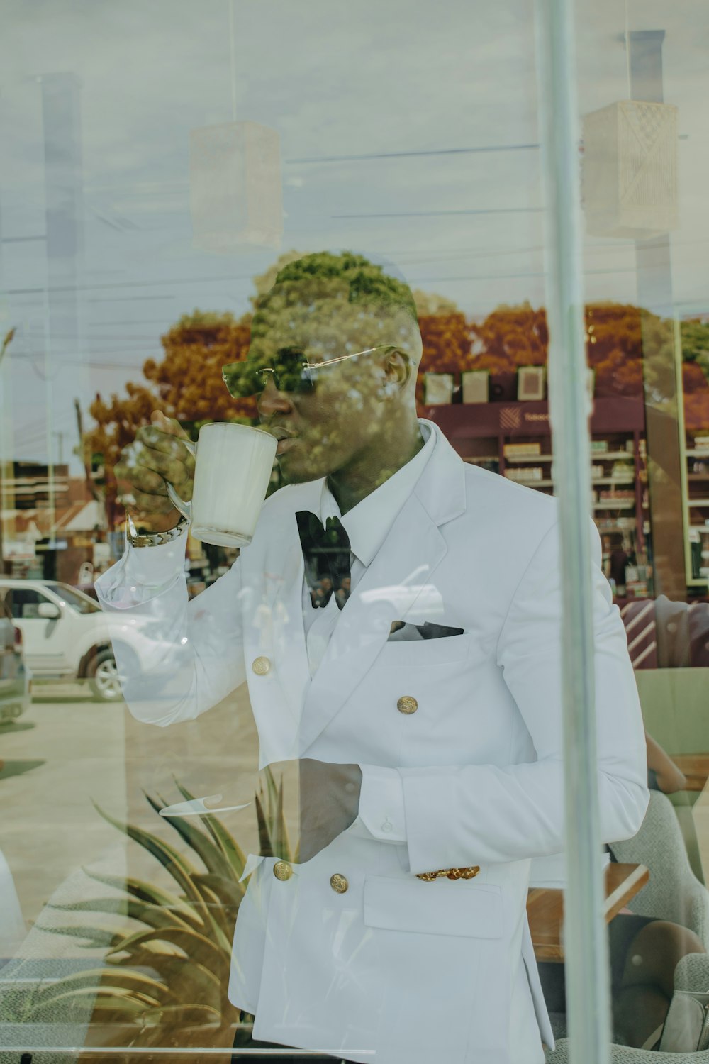 a man in a white suit holding a glass of wine