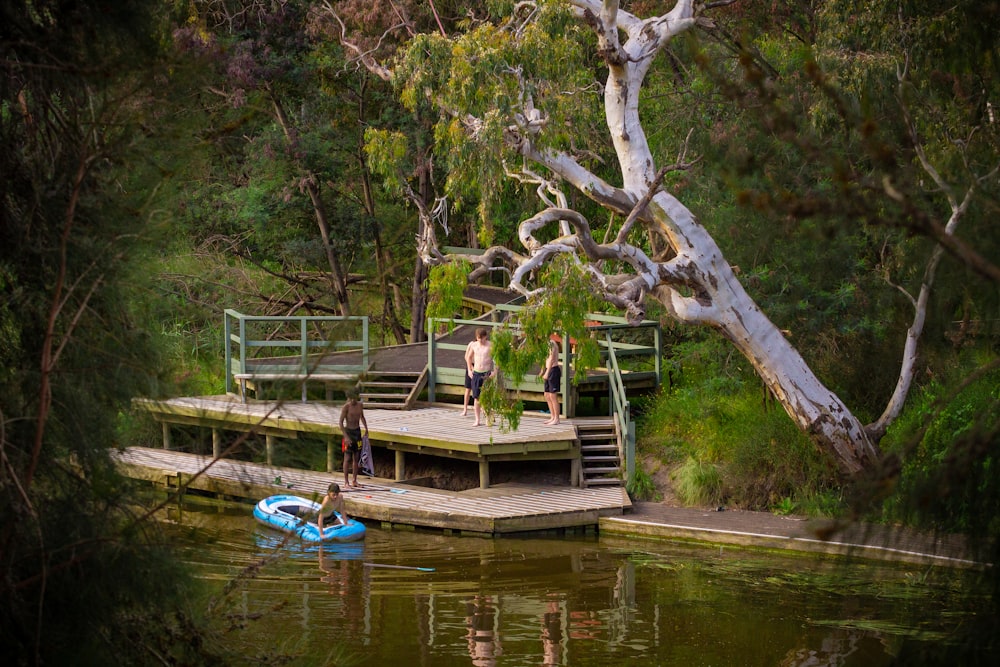 a group of people standing on a dock next to a body of water