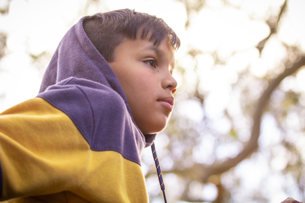 a young boy in a hoodie looking off into the distance