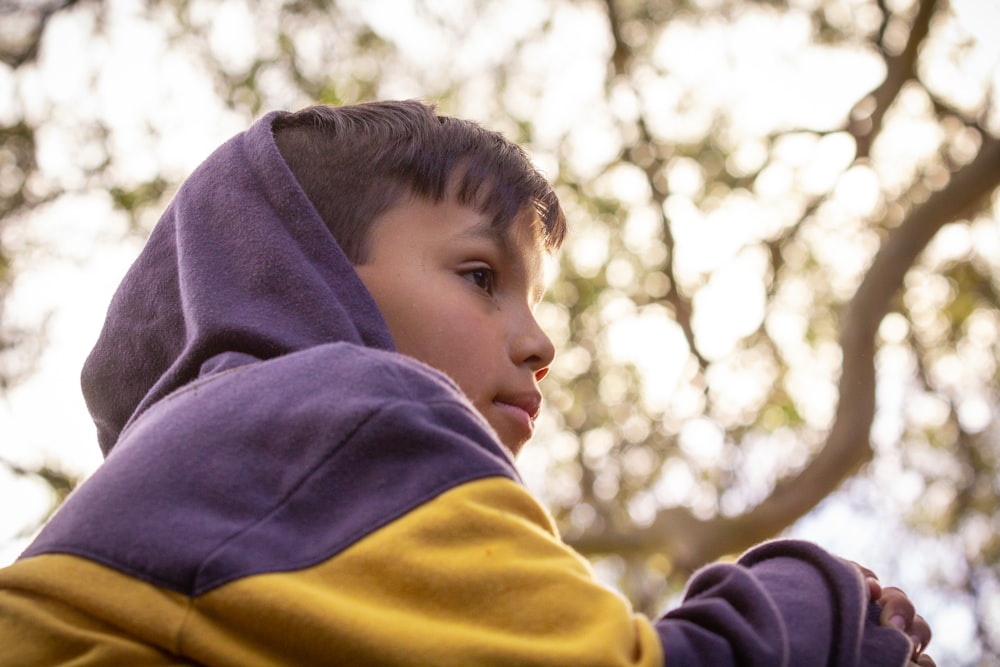 a young boy wearing a purple and yellow hoodie