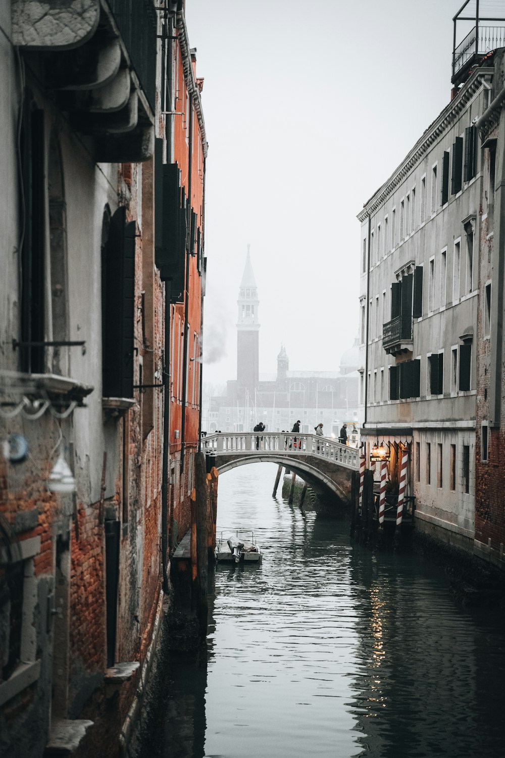 a canal with a bridge and a clock tower in the background