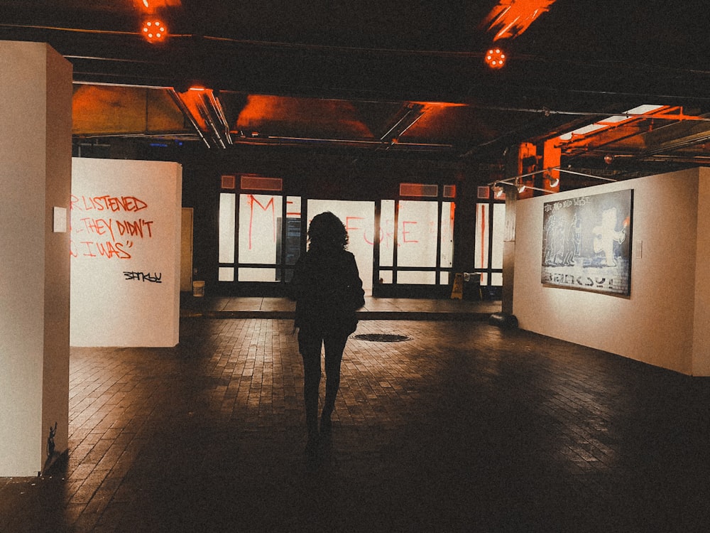 a person walking in a dark room with graffiti on the walls