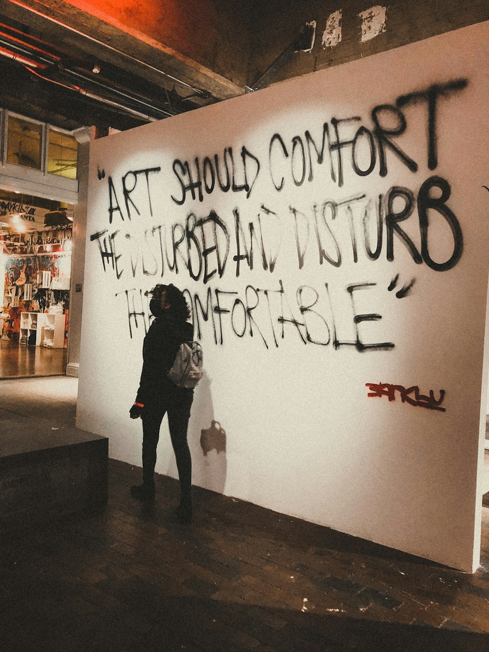 a person standing in front of a wall with graffiti on it