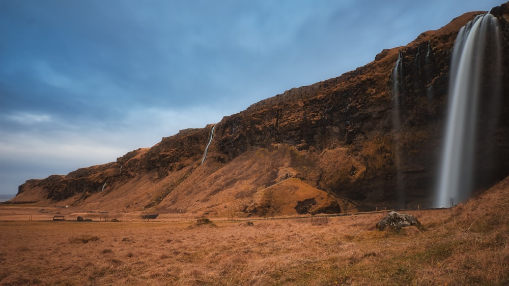 a waterfall in the middle of a grassy field
