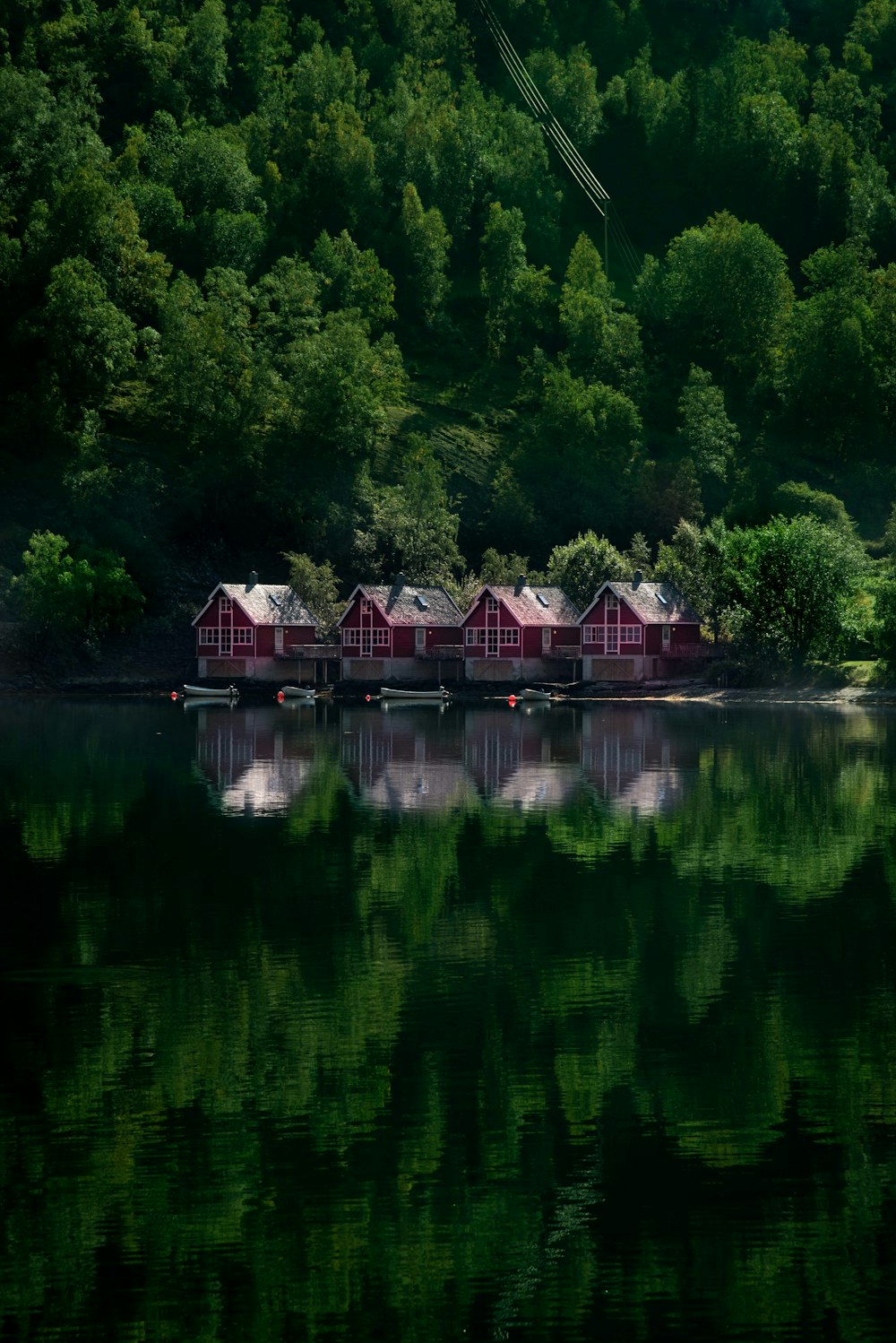 a row of red cabins sitting on top of a lake
