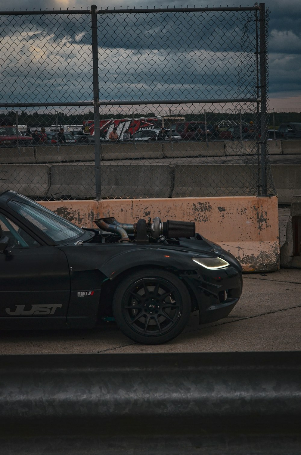 a black sports car parked in front of a fence