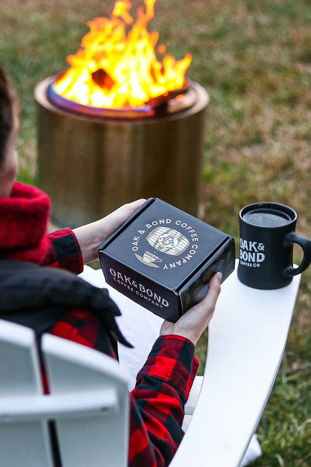 a person sitting in a chair next to a fire pit holding a book