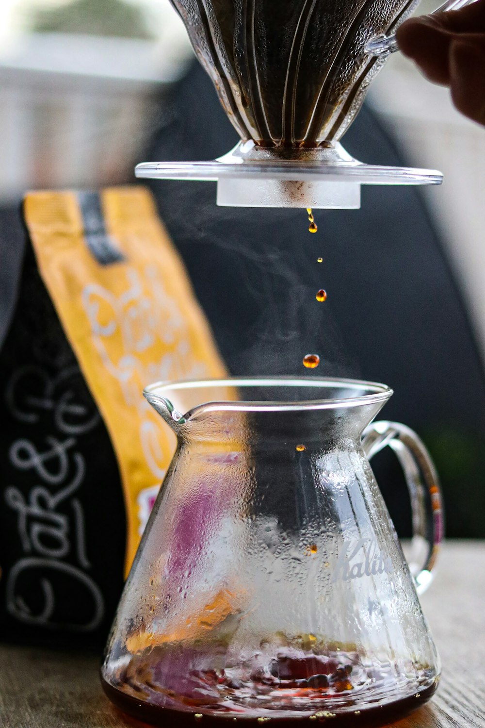 a person pours coffee into a glass carafe