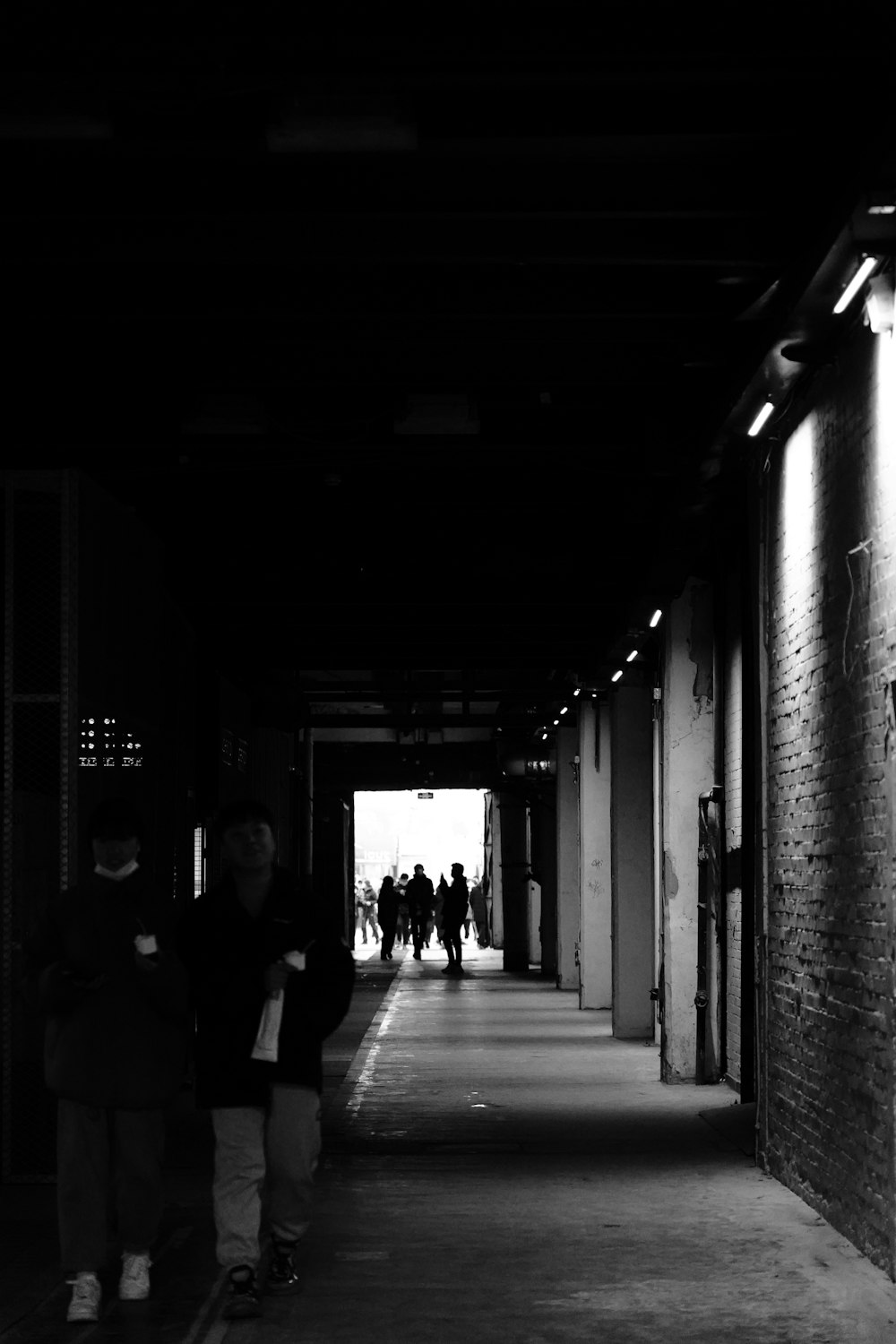 a black and white photo of people walking down a hallway