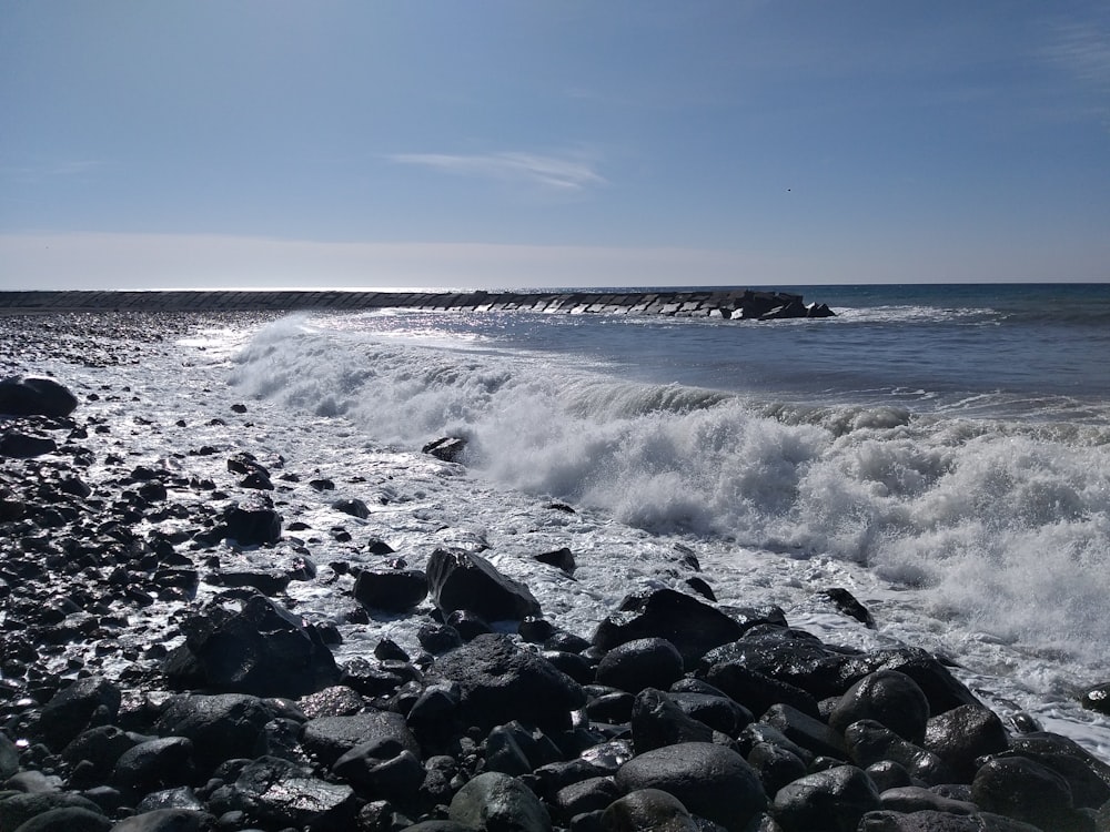 a rocky beach with a wave coming in to shore