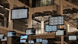 a bunch of television screens hanging from the ceiling