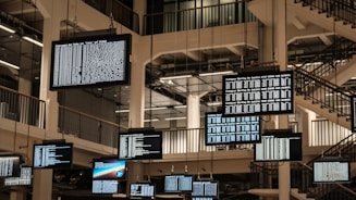 a bunch of television screens hanging from the ceiling