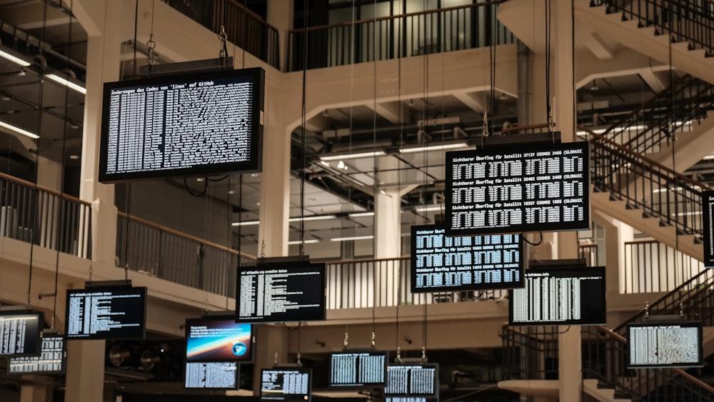 a bunch of television screens hanging from the ceiling