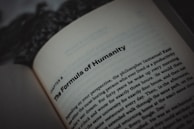An open book displaying text, with a focus on the title, 'The Formula of Humanity.' The page is part of a chapter, with surrounding text visible in smaller font. The background is blurry, emphasizing the text.