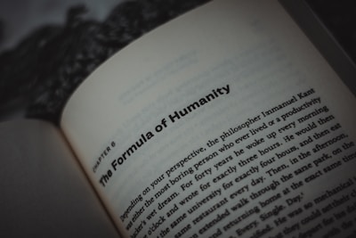 An open book displaying text, with a focus on the title, 'The Formula of Humanity.' The page is part of a chapter, with surrounding text visible in smaller font. The background is blurry, emphasizing the text.