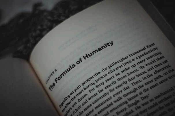 An open book displaying text, with a focus on the title, 'The Formula of Humanity.' The page is part of a chapter, with surrounding text visible in smaller font. The background is blurry, emphasizing the text.