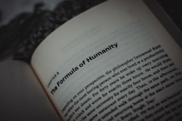 An open book displaying text, with a focus on the title, 'The Formula of Humanity.' The page is part of a chapter, with surrounding text visible in smaller font. The background is blurry, emphasizing the text.
