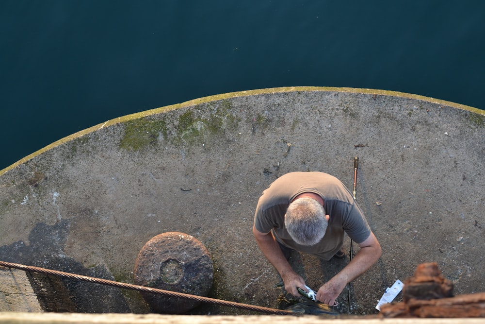 a man standing on top of a cement wall next to a body of water