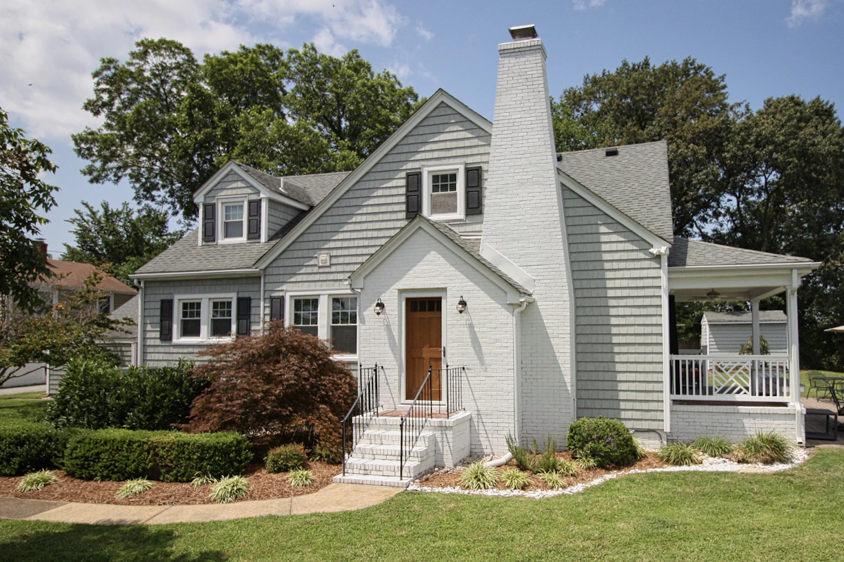 a gray house with a white porch and a brown door