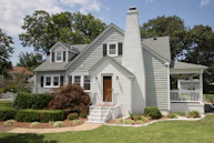 a gray house with a white porch and a brown door