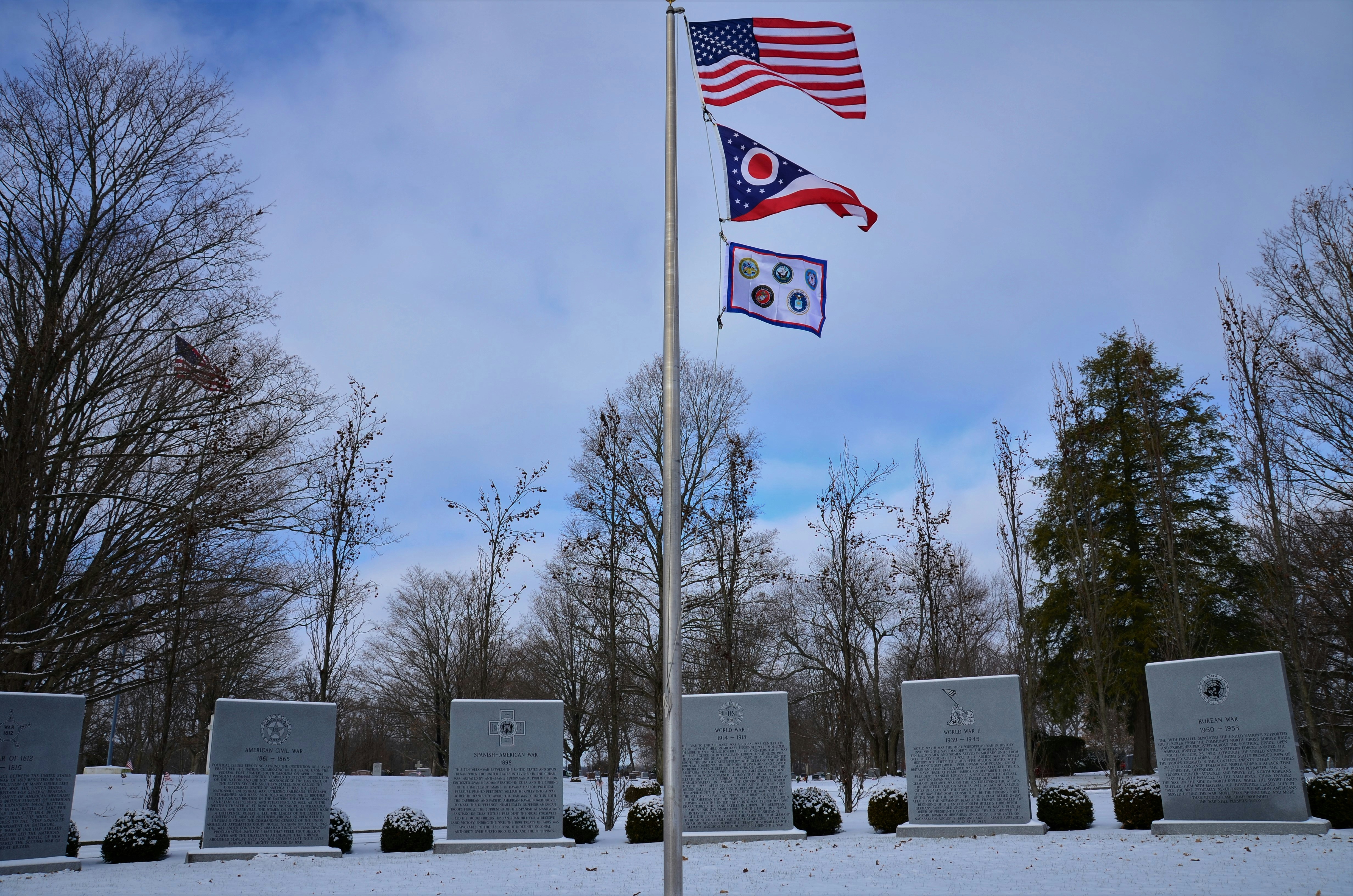 two flags are flying in a snowy cemetery