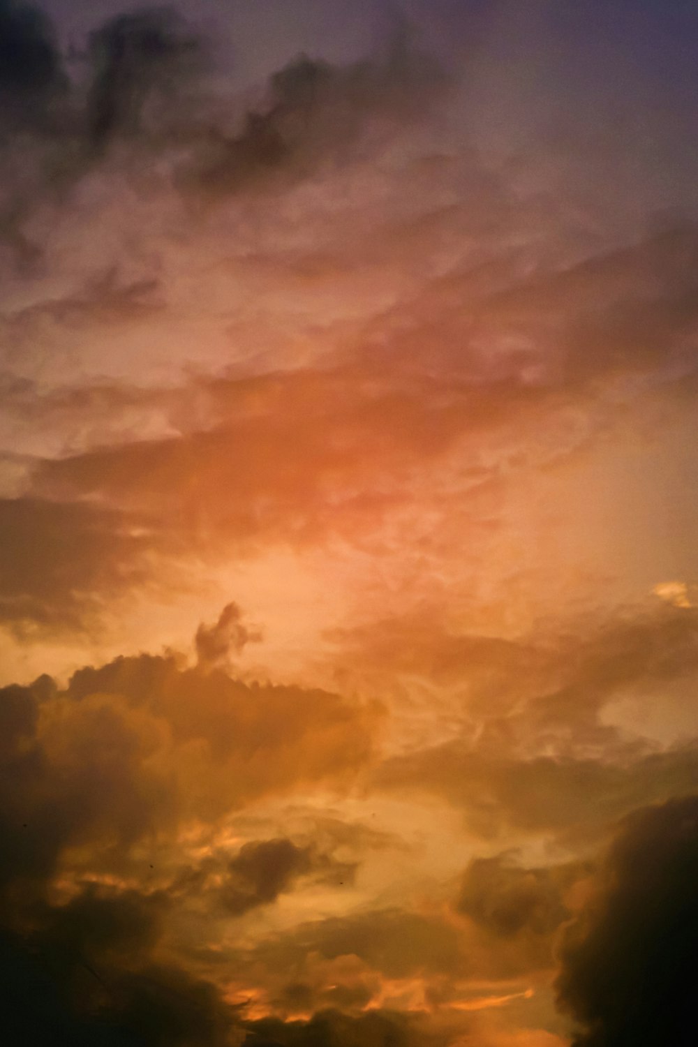 a plane flying through a cloudy sky at sunset