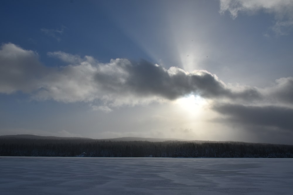 the sun is shining through the clouds over the snow