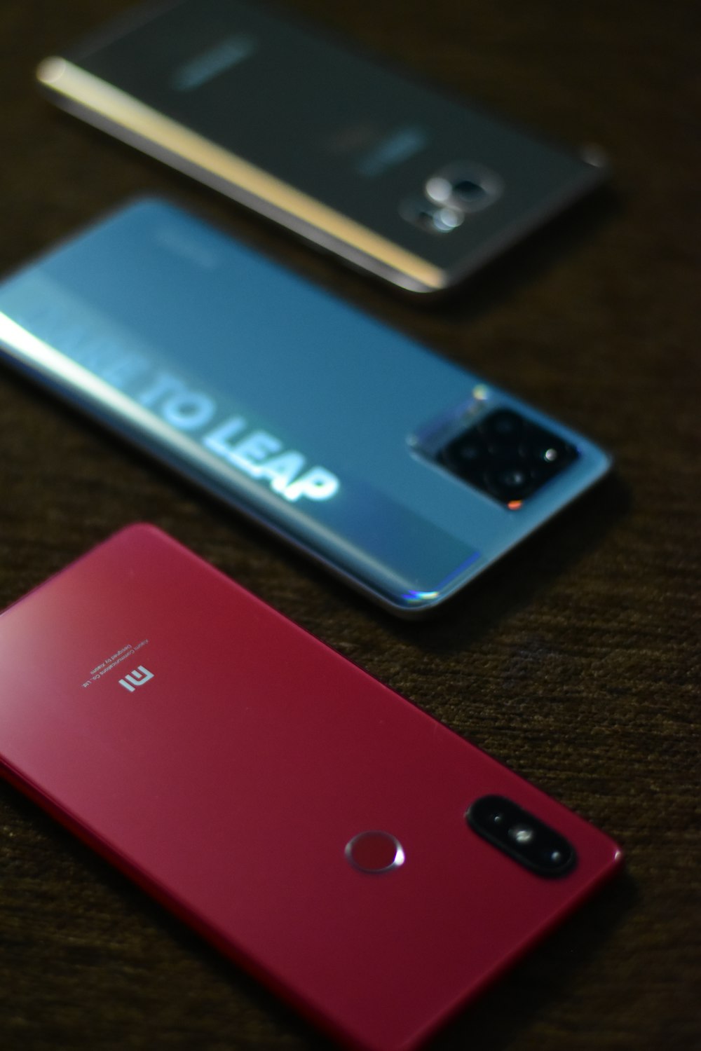 three different colored cell phones sitting on a table