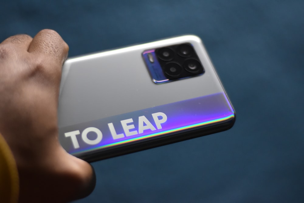 a hand holding a samsung phone with a to leap sticker on it