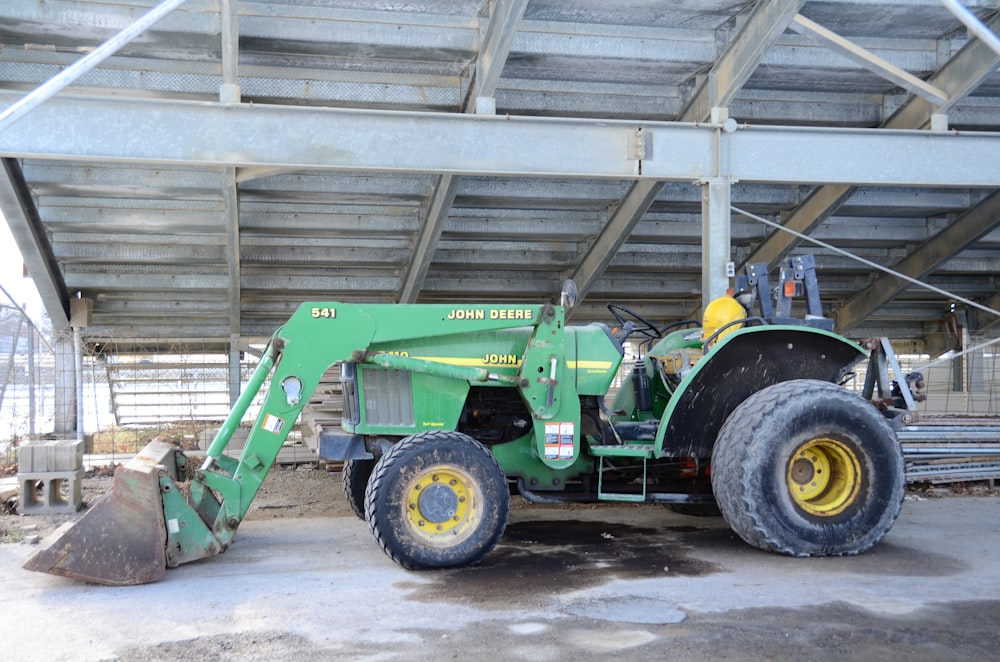 a green tractor parked under a metal structure