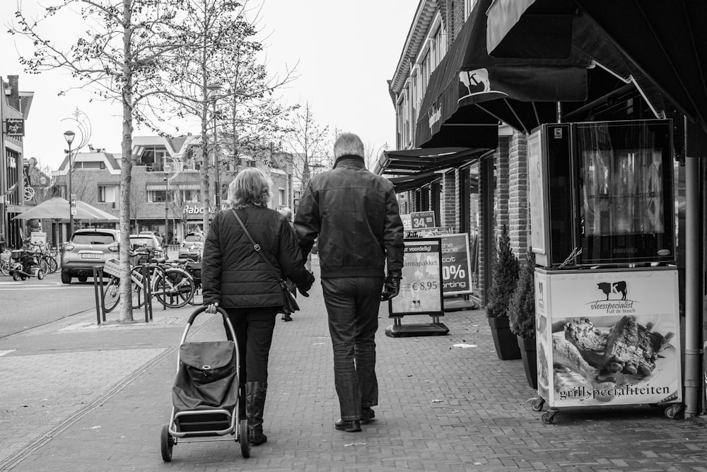 a man and a woman walking down a street with a stroller