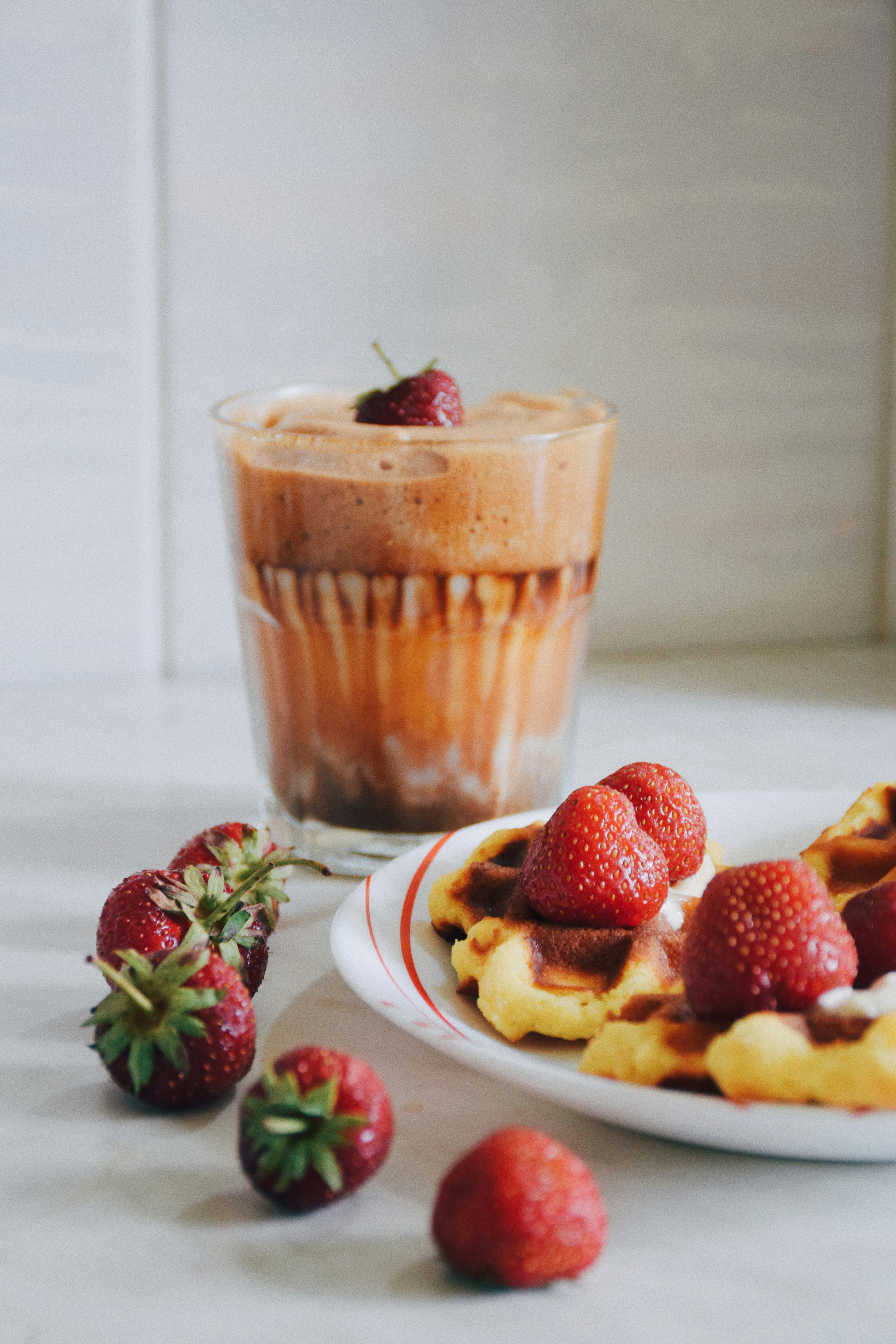 a plate of waffles with strawberries and a cup of coffee