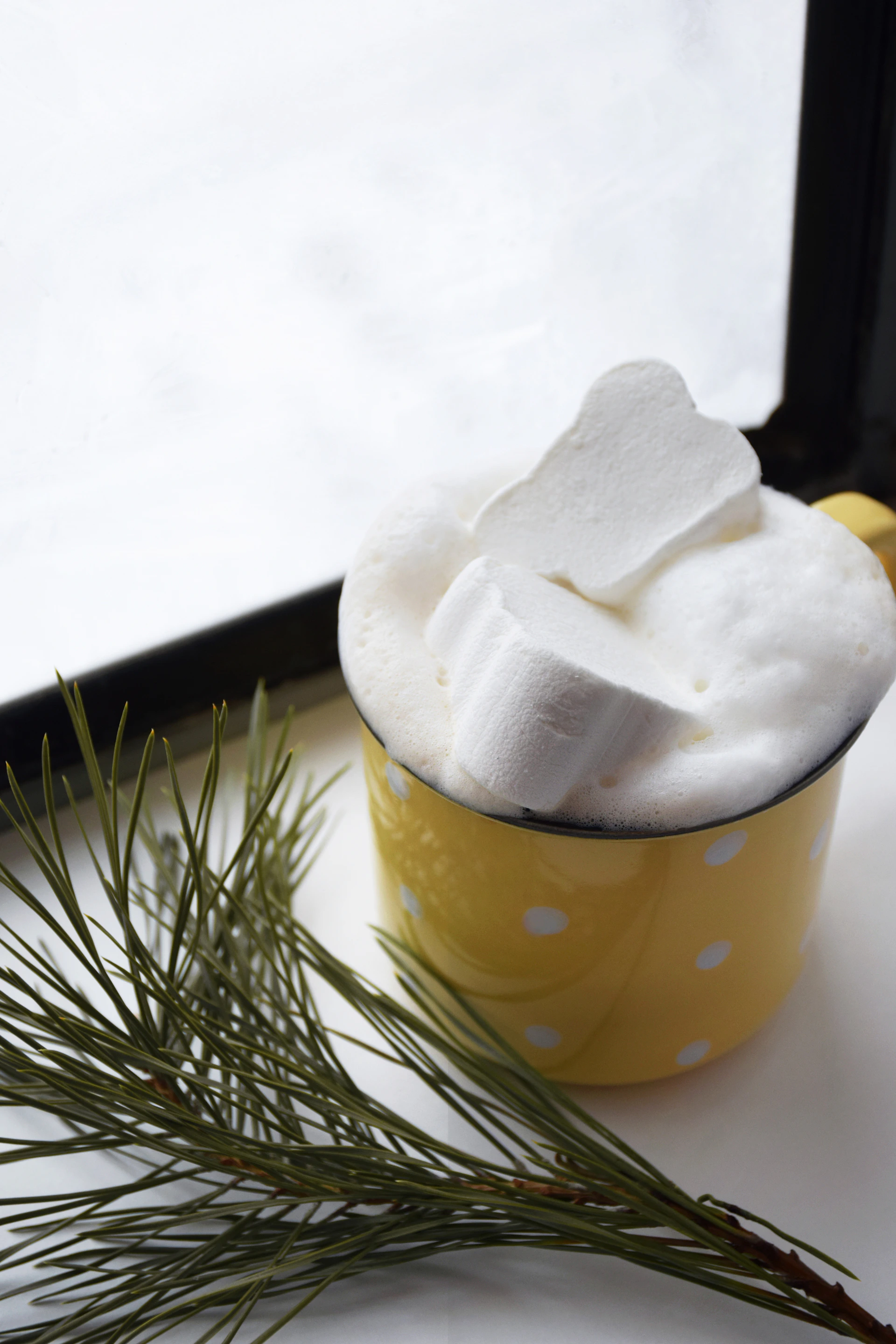 a cup filled with marshmallows sitting next to a window