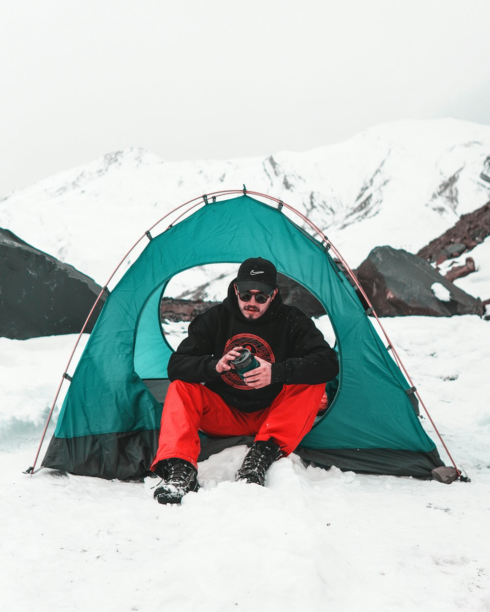 a man sitting in front of a tent in the snow