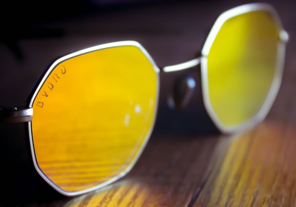 a pair of yellow sunglasses sitting on top of a wooden table