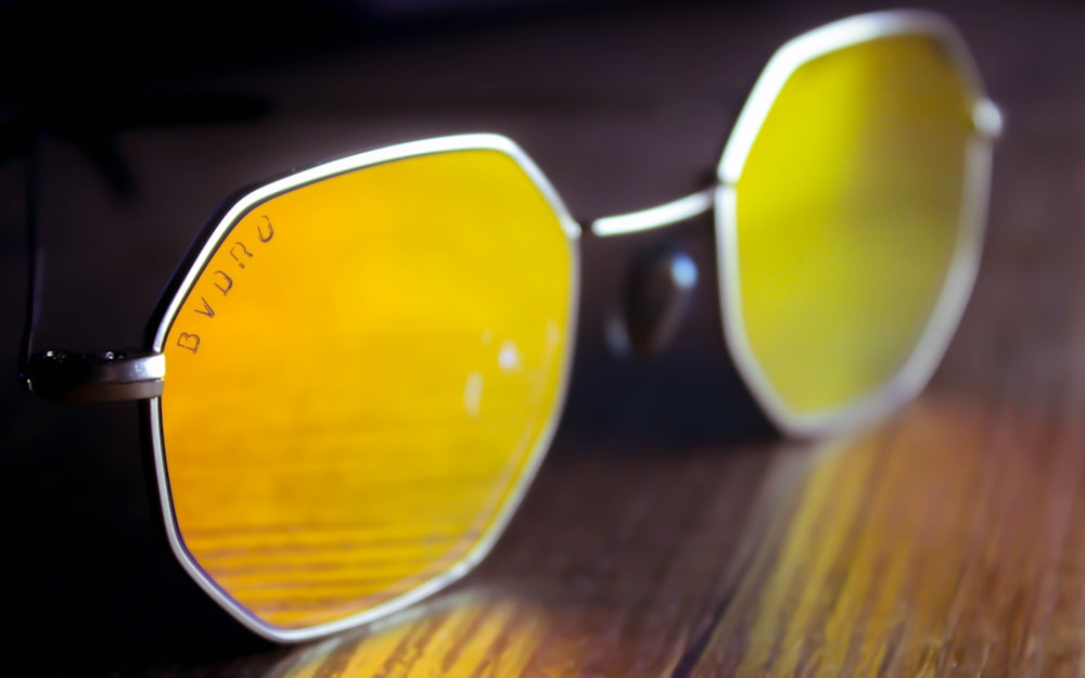 a pair of yellow sunglasses sitting on top of a wooden table