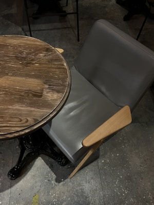 An elegant accent chair crafted from rich wood and iron, placed beside a rustic wooden table.