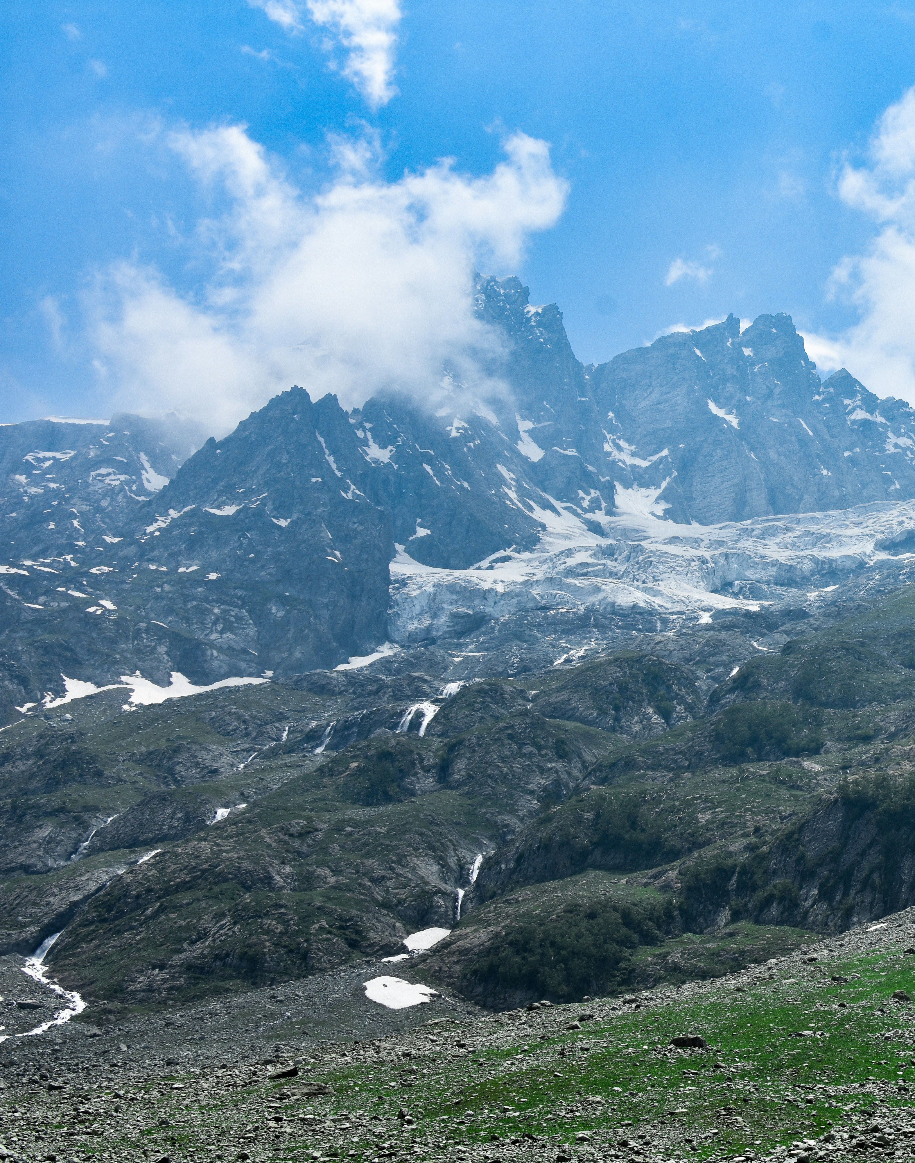 a mountain range covered in snow and green grass