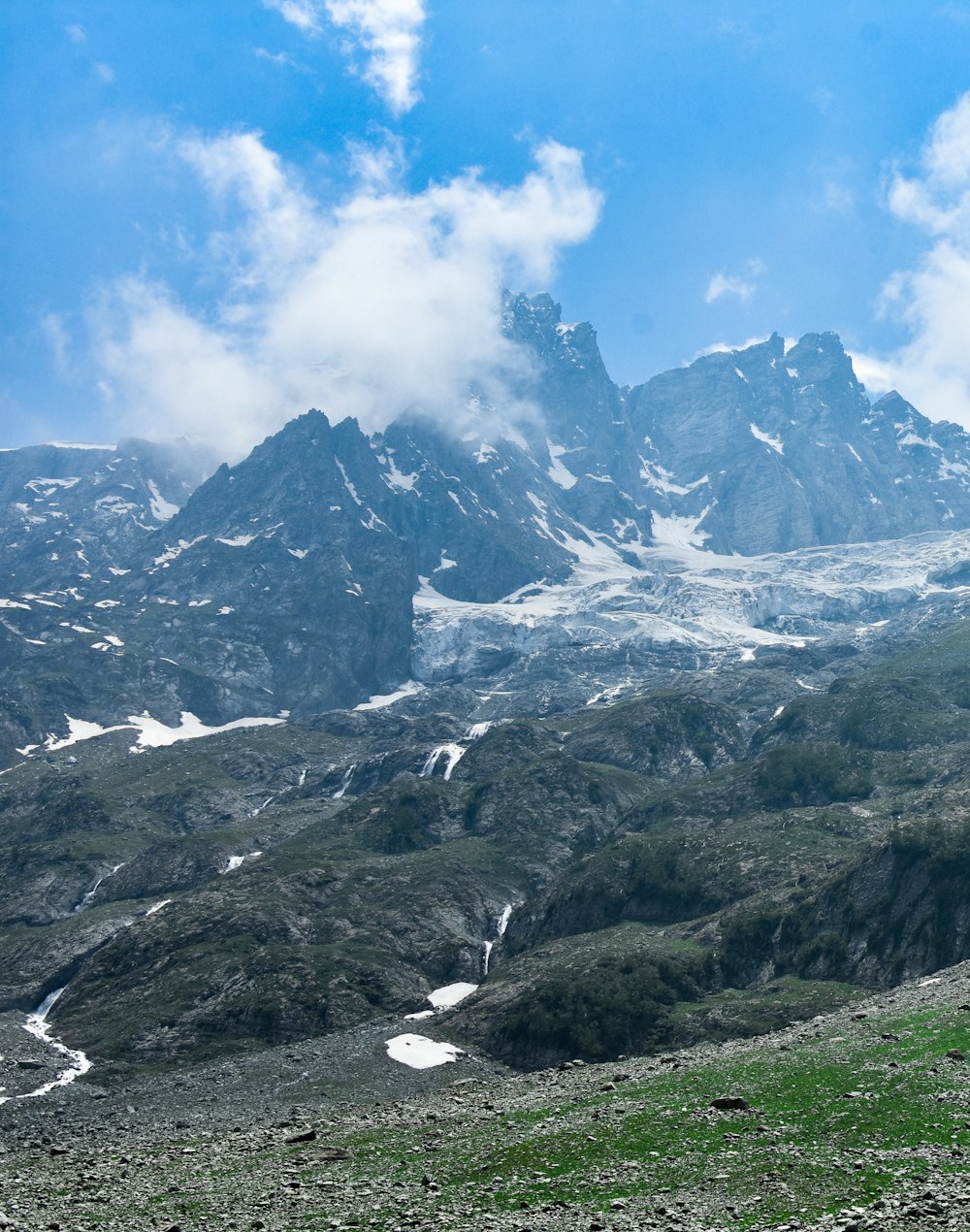 a mountain range covered in snow and green grass