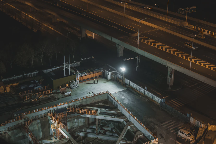 Verlichte bouwplaats in de nacht, van bovenaf gezien